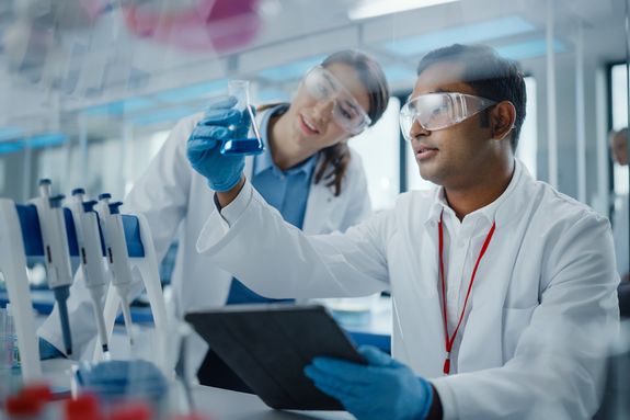Modern Medical Research Laboratory: Two Scientists Working Together Analysing Chemicals in Laboratory Flask